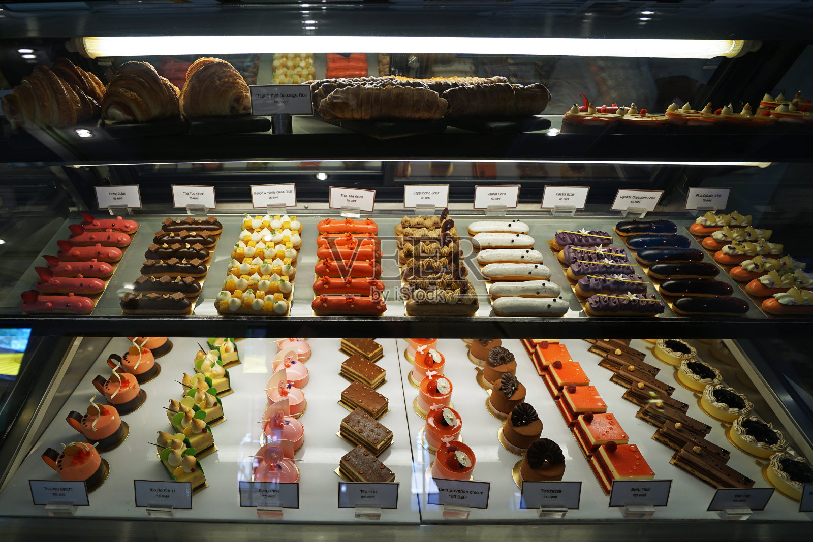 五颜六色的泡芙和法式糕点陈列在玻璃橱窗里照片摄影图片