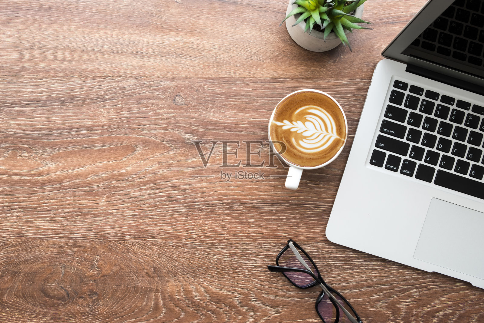 木质办公桌，配有笔记本电脑、咖啡、笔和仙人掌。顶视图，扁平风格，含复制空间。照片摄影图片