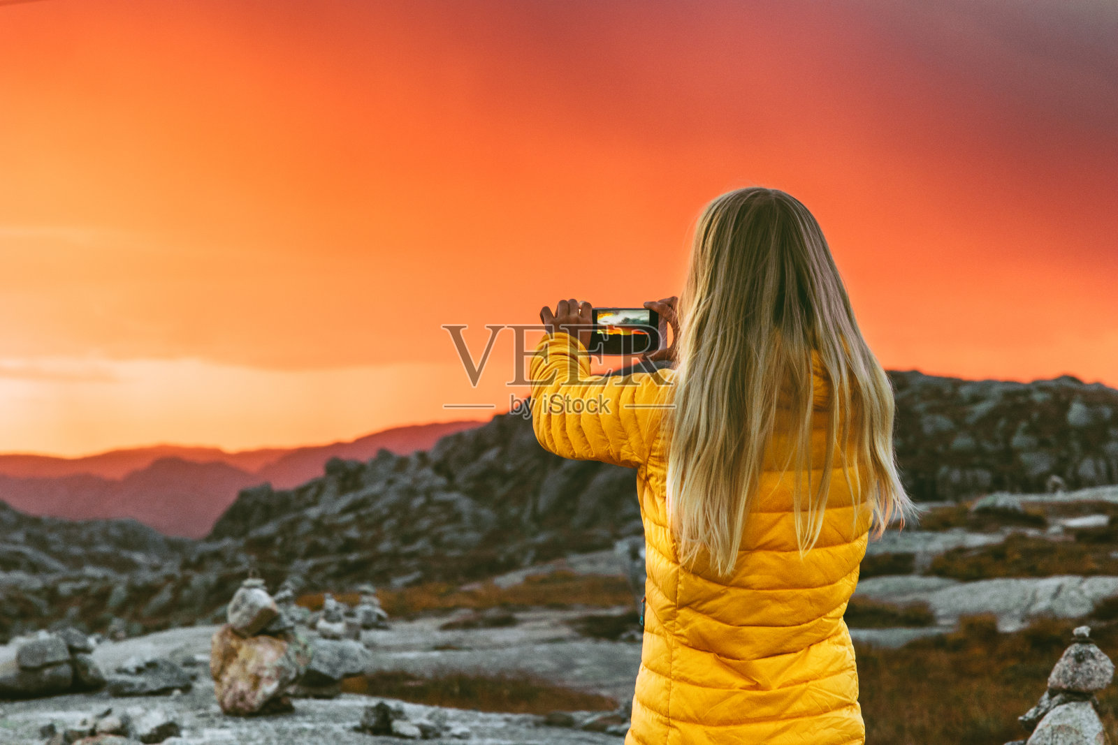 女人用智能手机拍摄日落山景，旅行生活方式与现代科技概念照片摄影图片