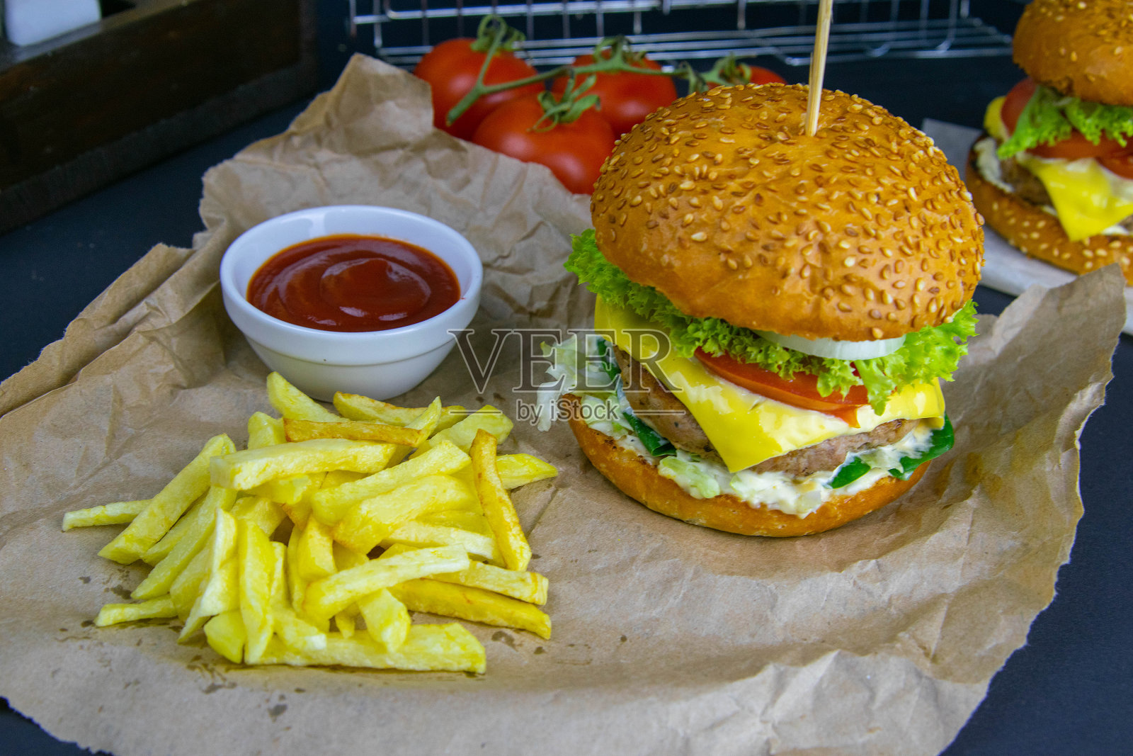 特写汉堡，酱汁，炸薯条和西红柿摊位附近，烧烤架在背景照片摄影图片