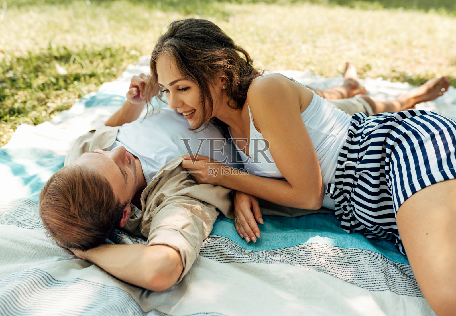 阳光明媚的日子里，情侣在公园户外约会。浪漫情侣在草地上野餐，享受幸福关系照片摄影图片
