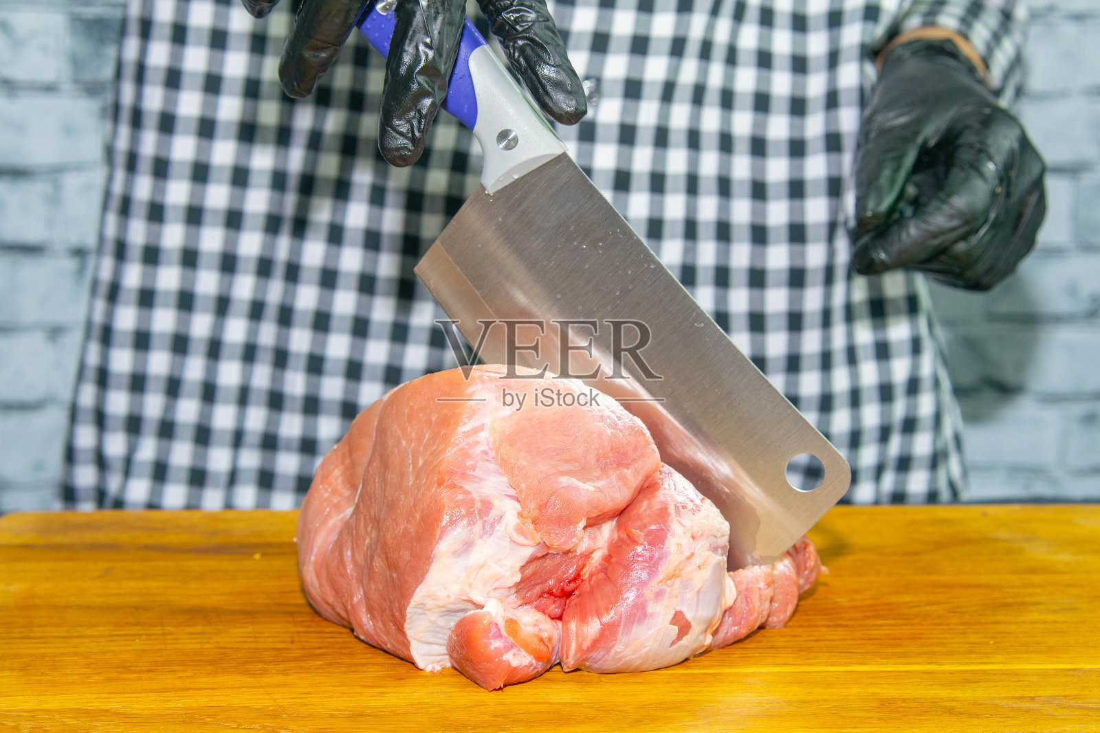 女性双手戴黑手套切多汁猪肉照片摄影图片