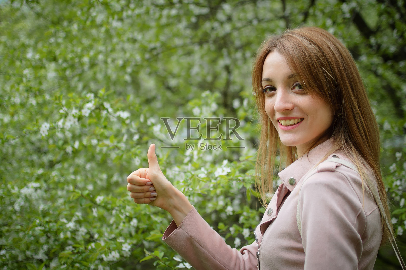 户外人像：花园中开花的树背景上快乐微笑的女人，早春，停止过敏概念照片摄影图片