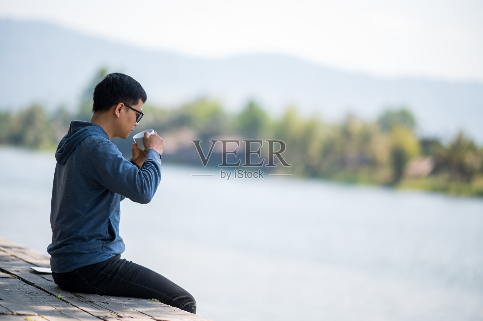 假期里在户外咖啡馆看书、喝咖啡、放松的年轻男人照片摄影图片