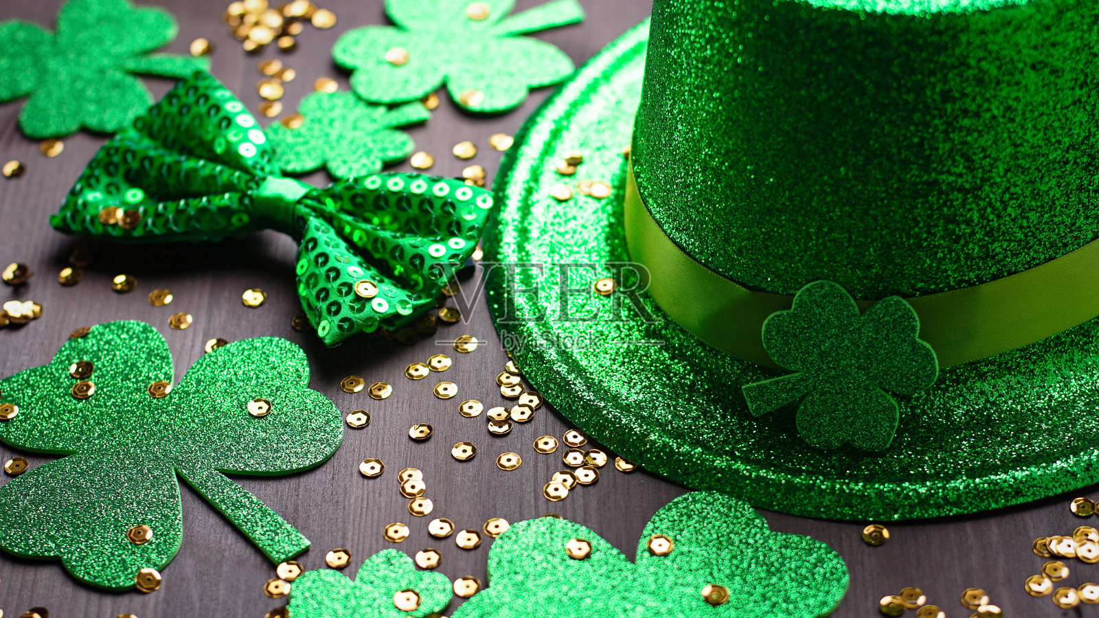 圣帕特里克节贺卡，带有传统符号，三叶草，绿色服装。绿色的帽子，领结，圣帕特里克节三叶草，金色的纸屑在深色的木制背景，复制空间照片摄影图片
