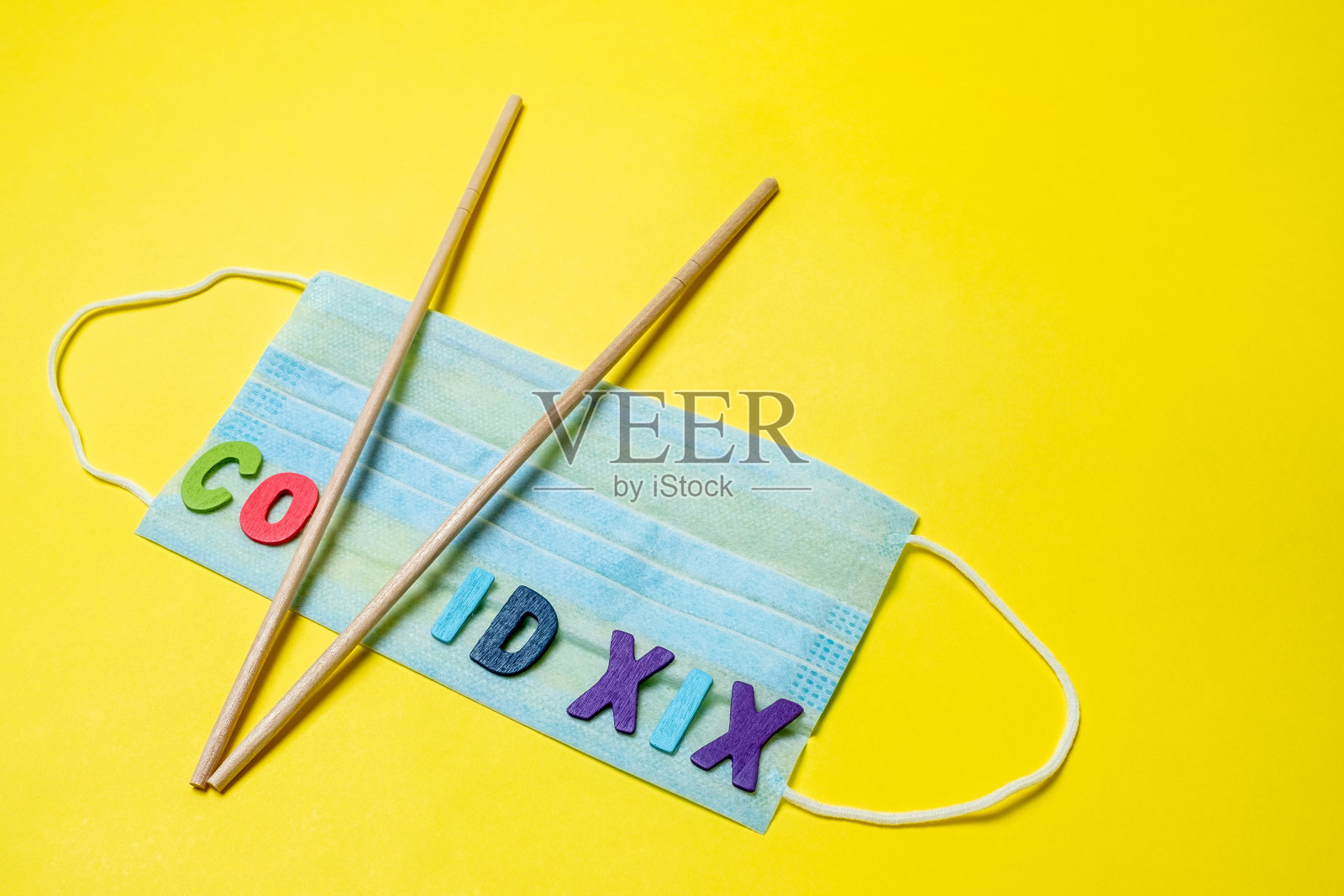 黄色背景的黑色医用口罩和字母v形状的亚洲筷子。照片摄影图片