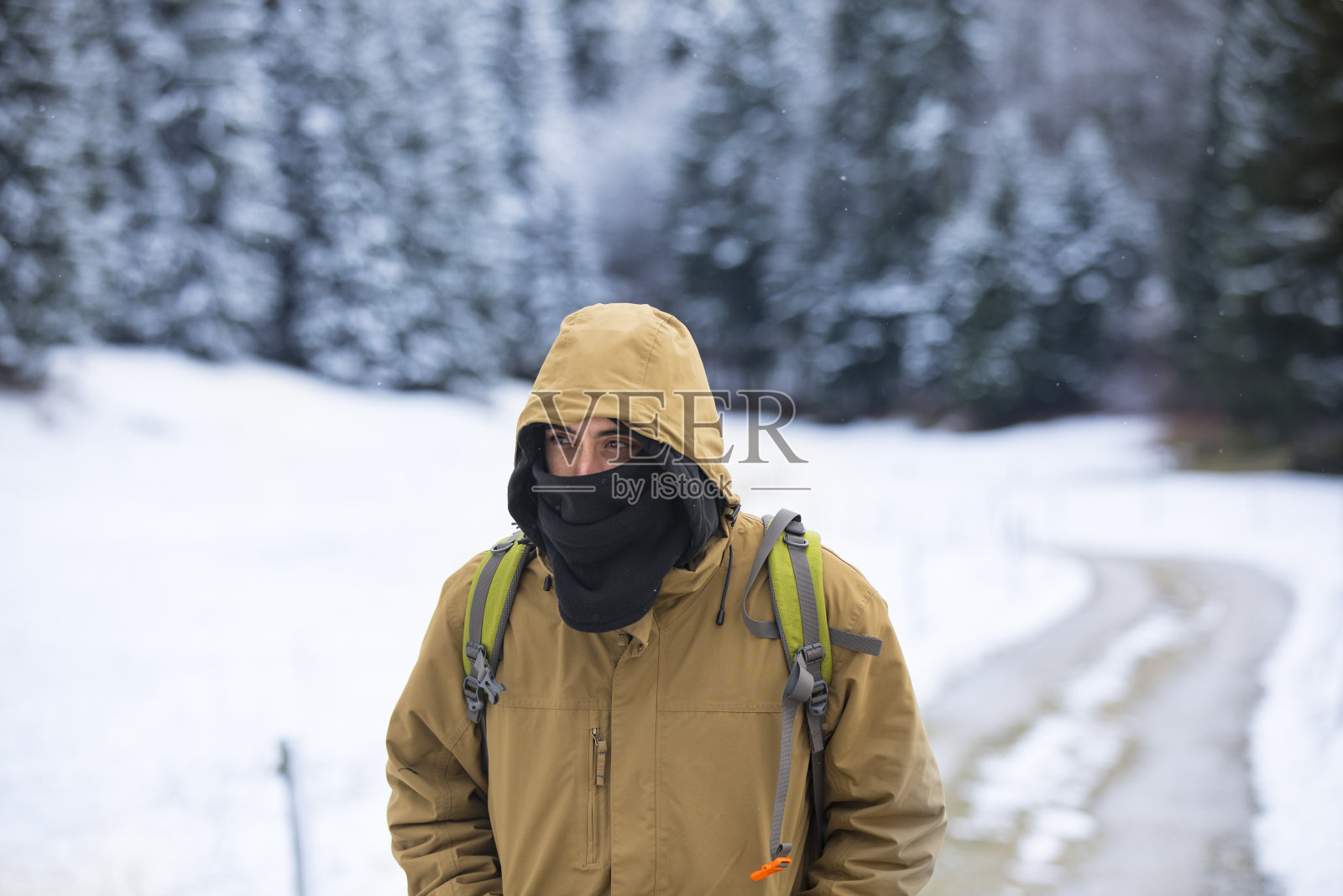 年轻的成年人在寒冷的雪景土路上徒步旅行照片摄影图片
