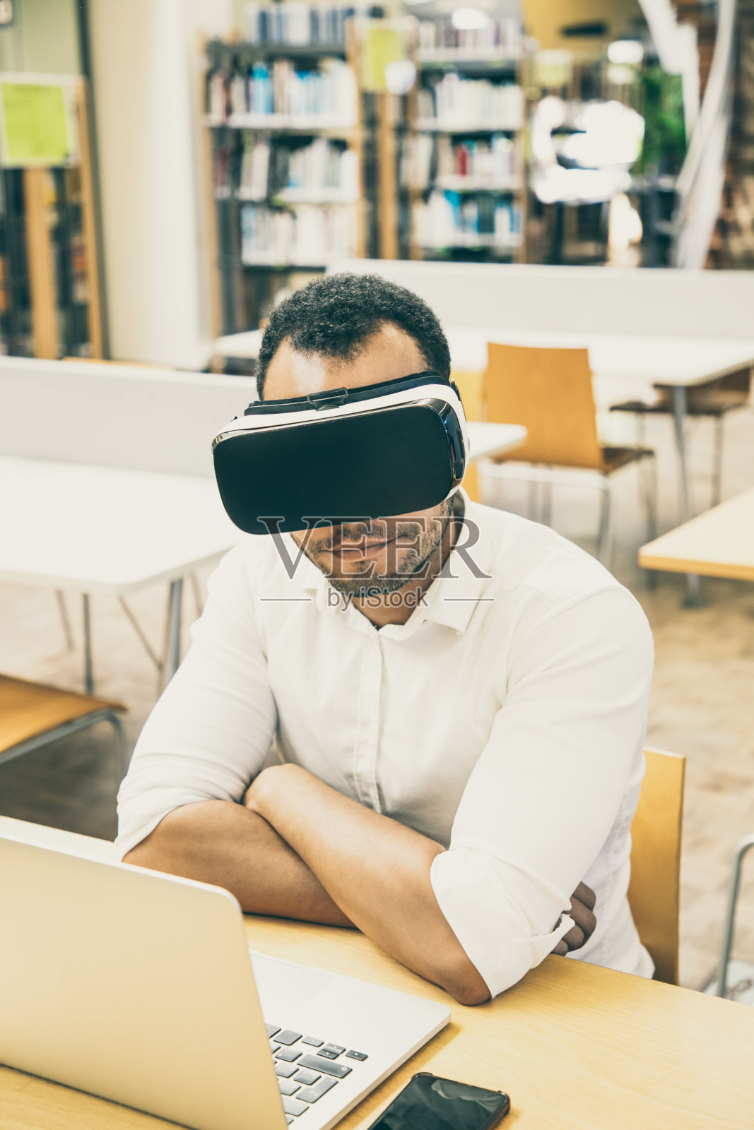 戴着VR眼镜用笔记本电脑学习的男学生照片摄影图片