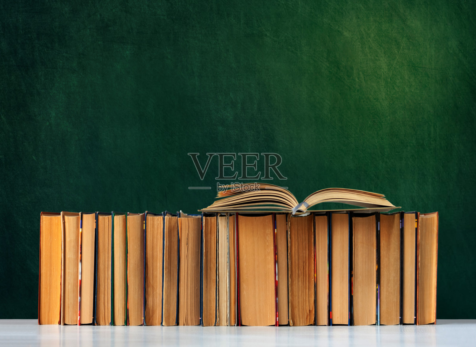 回到学校，堆着书本，带着空白的绿校板背景，教育理念照片摄影图片