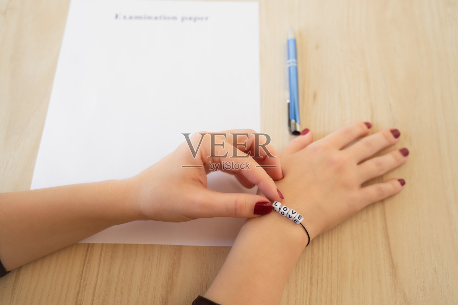 学生女孩手与手链和爱的话。在桌子上放一张空的试卷。高考时的初恋。概念照片摄影图片