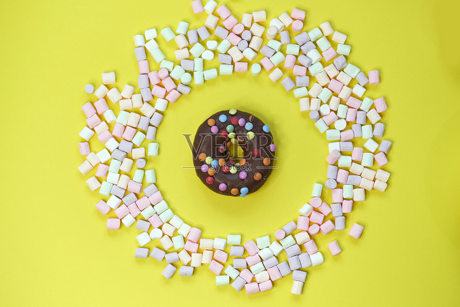 甜甜圈在一个圆形的棉花糖框架在黄色的背景。顶视图的照片照片摄影图片