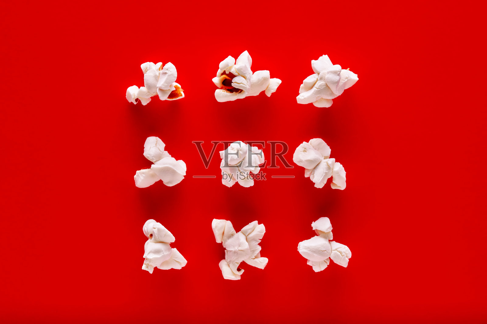 红色背景下的爆米花排成一排照片摄影图片