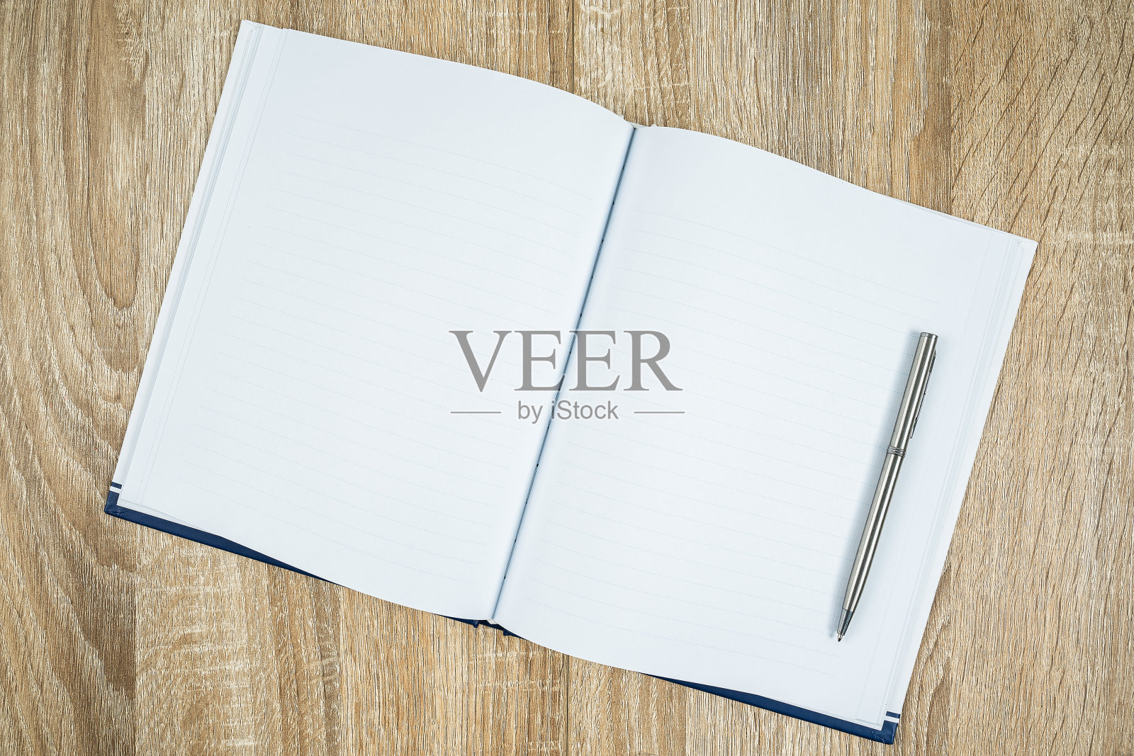 木桌上的空白记事本和银色钢笔照片摄影图片