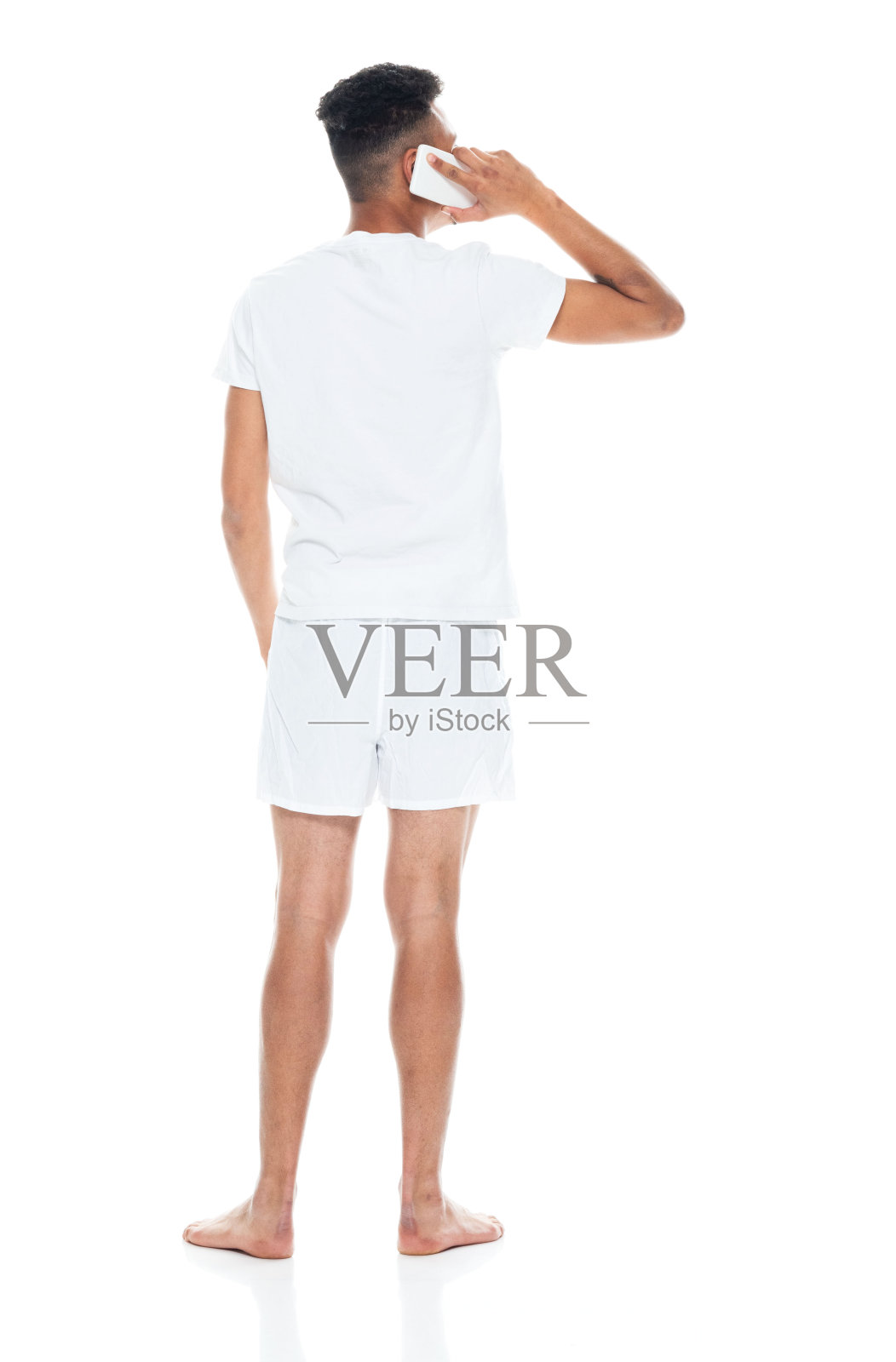 非裔美国青年男性穿着内衣站在白人背景前使用手机照片摄影图片