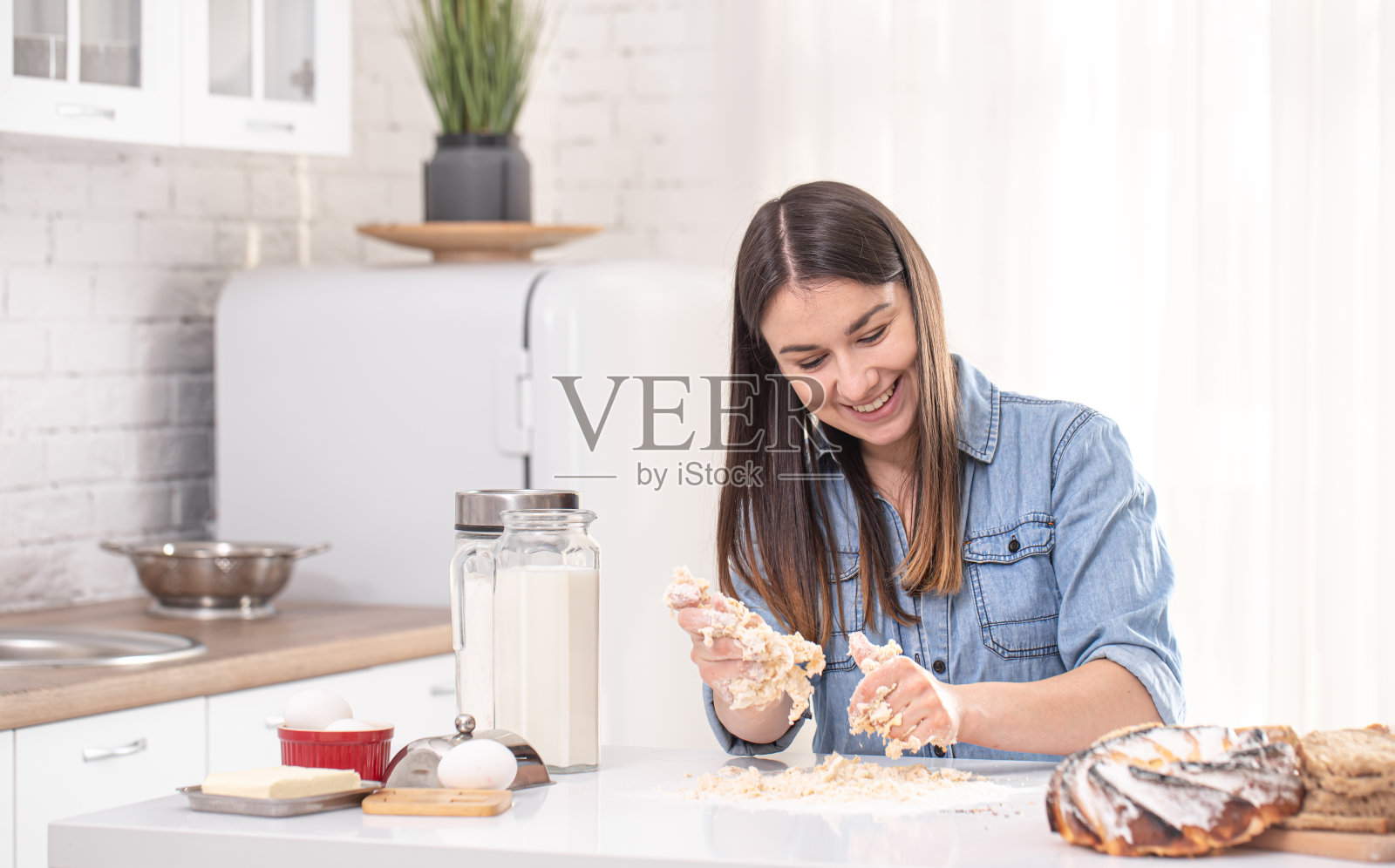一位年轻漂亮的女人在厨房里准备自制蛋糕。照片摄影图片