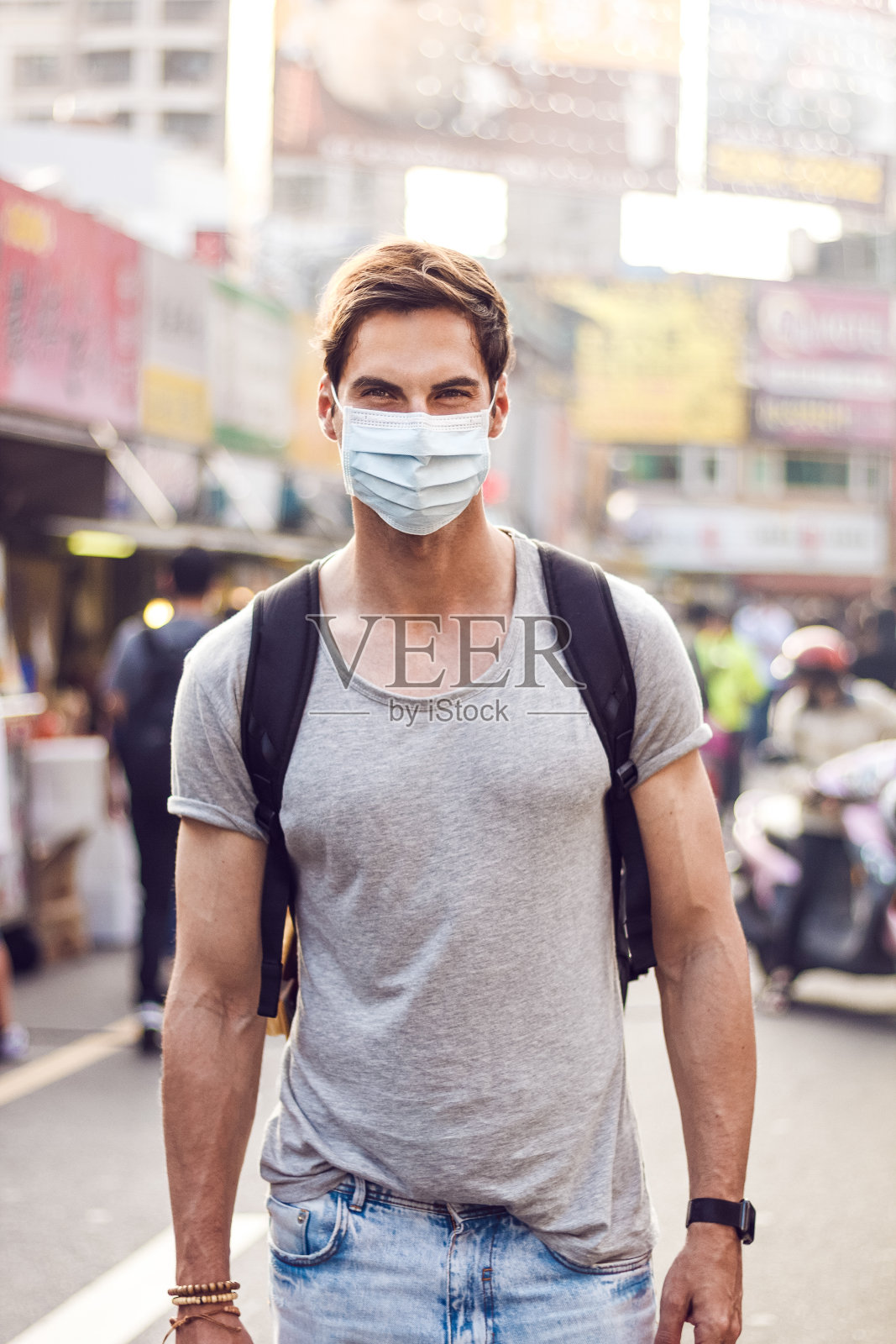 在受冠状病毒感染的城市中戴着外科口罩的男人照片摄影图片