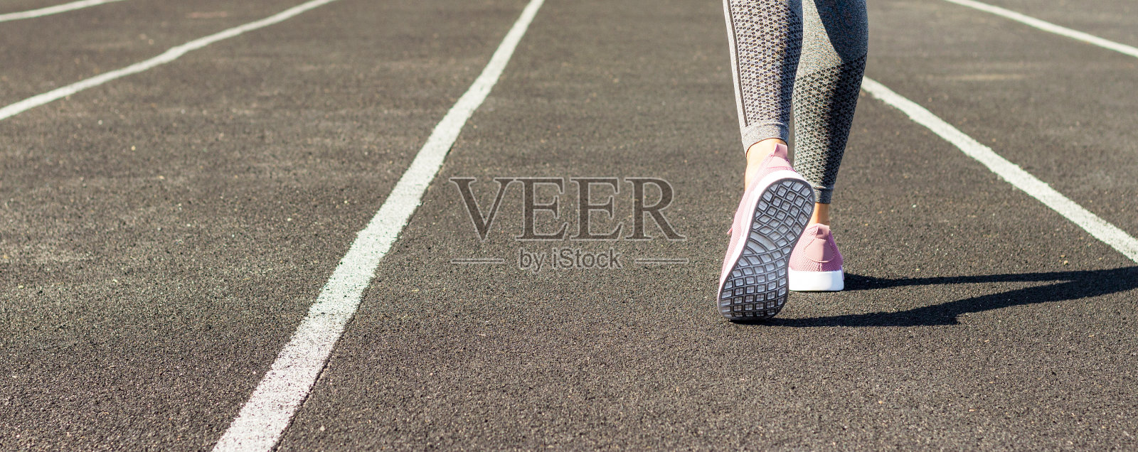 裁剪形象的女性运动腿和脚在跑步鞋在体育场照片摄影图片