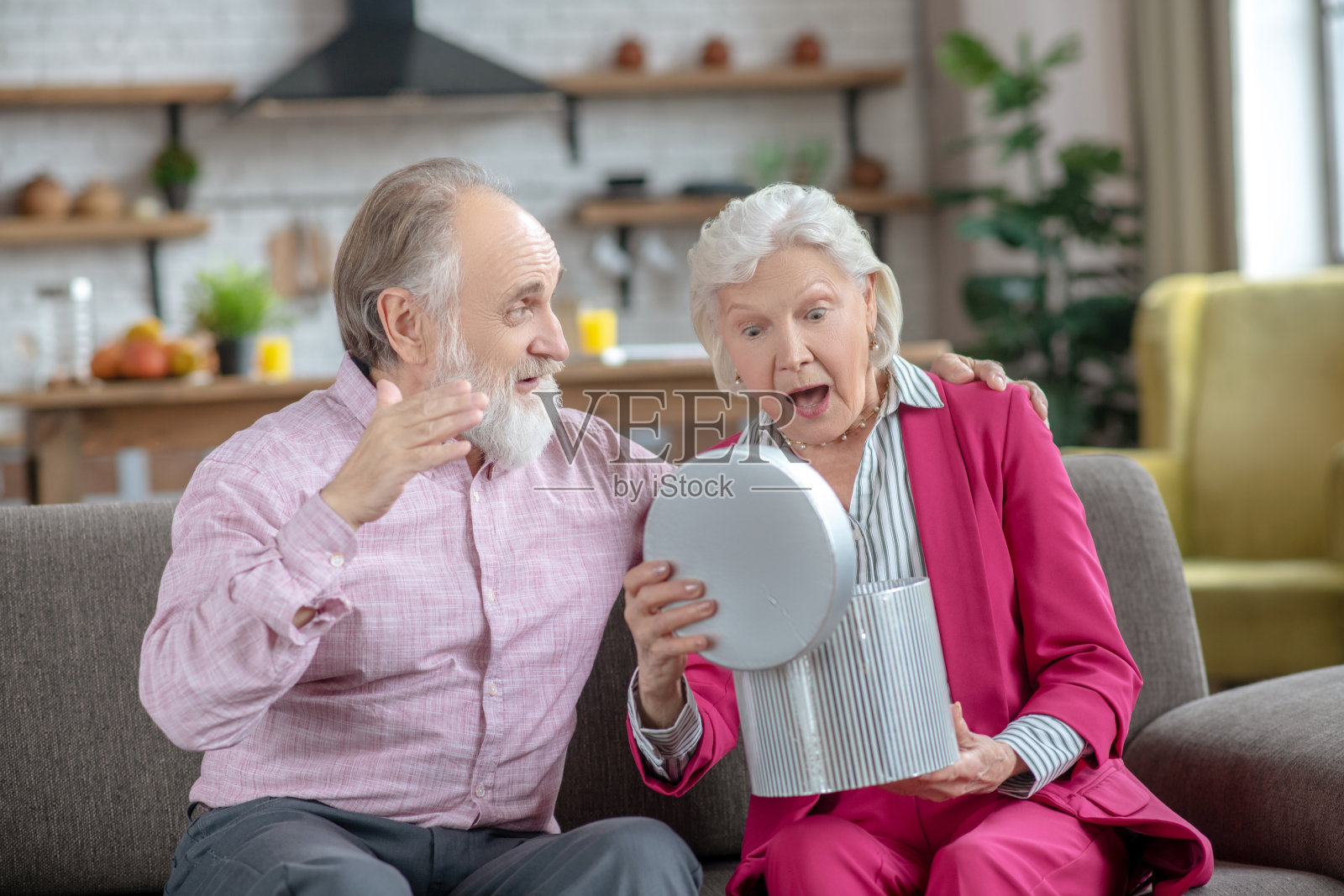 白发苍苍的老妇人打开礼品盒，看起来很惊讶照片摄影图片