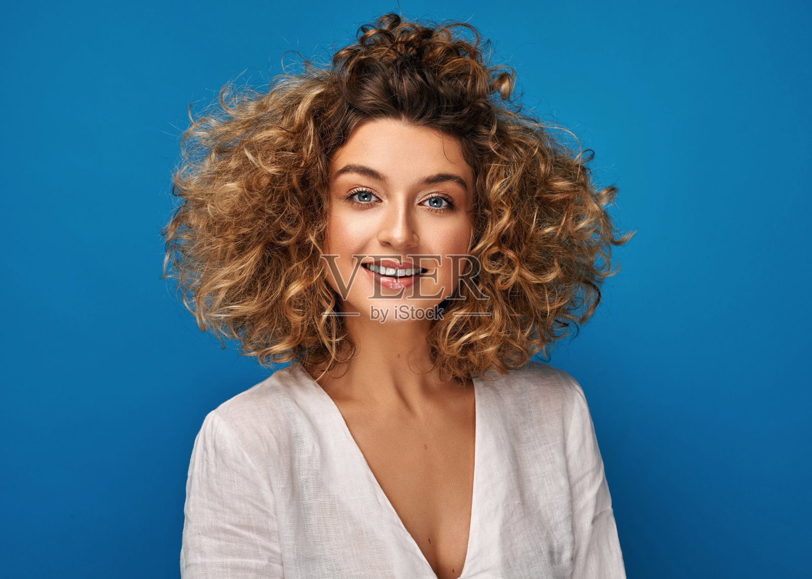 一个年轻开朗的女人被孤立在蓝色背景上的肖像照片摄影图片