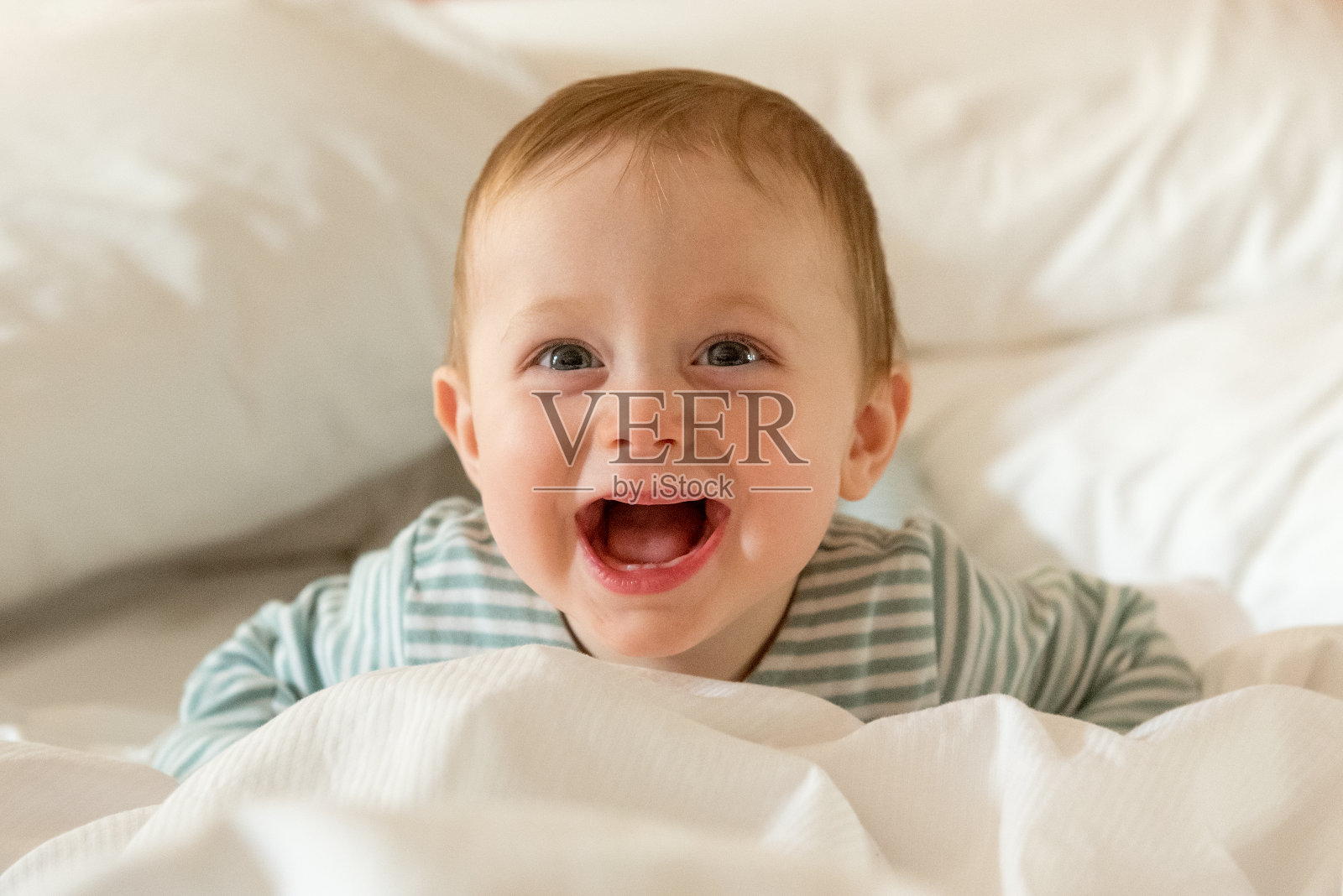 8个月大的男婴躺在白色的床上微笑照片摄影图片