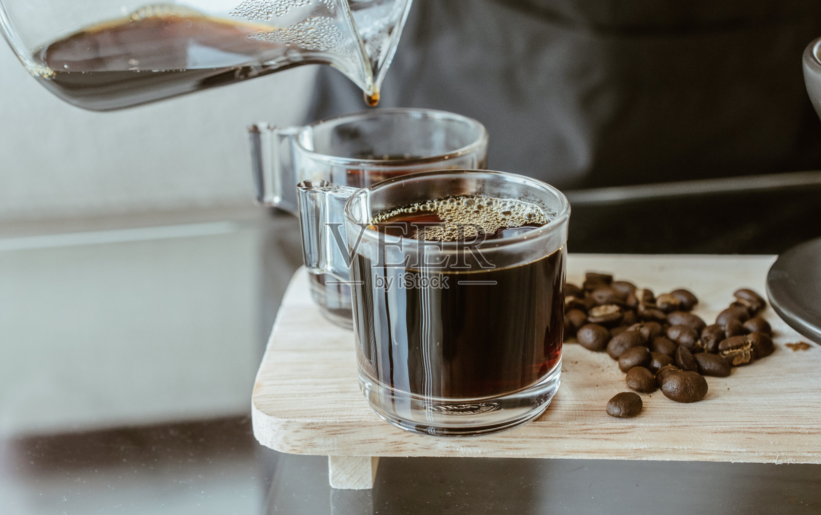 咖啡师将一杯热咖啡滴入一杯咖啡中。照片摄影图片