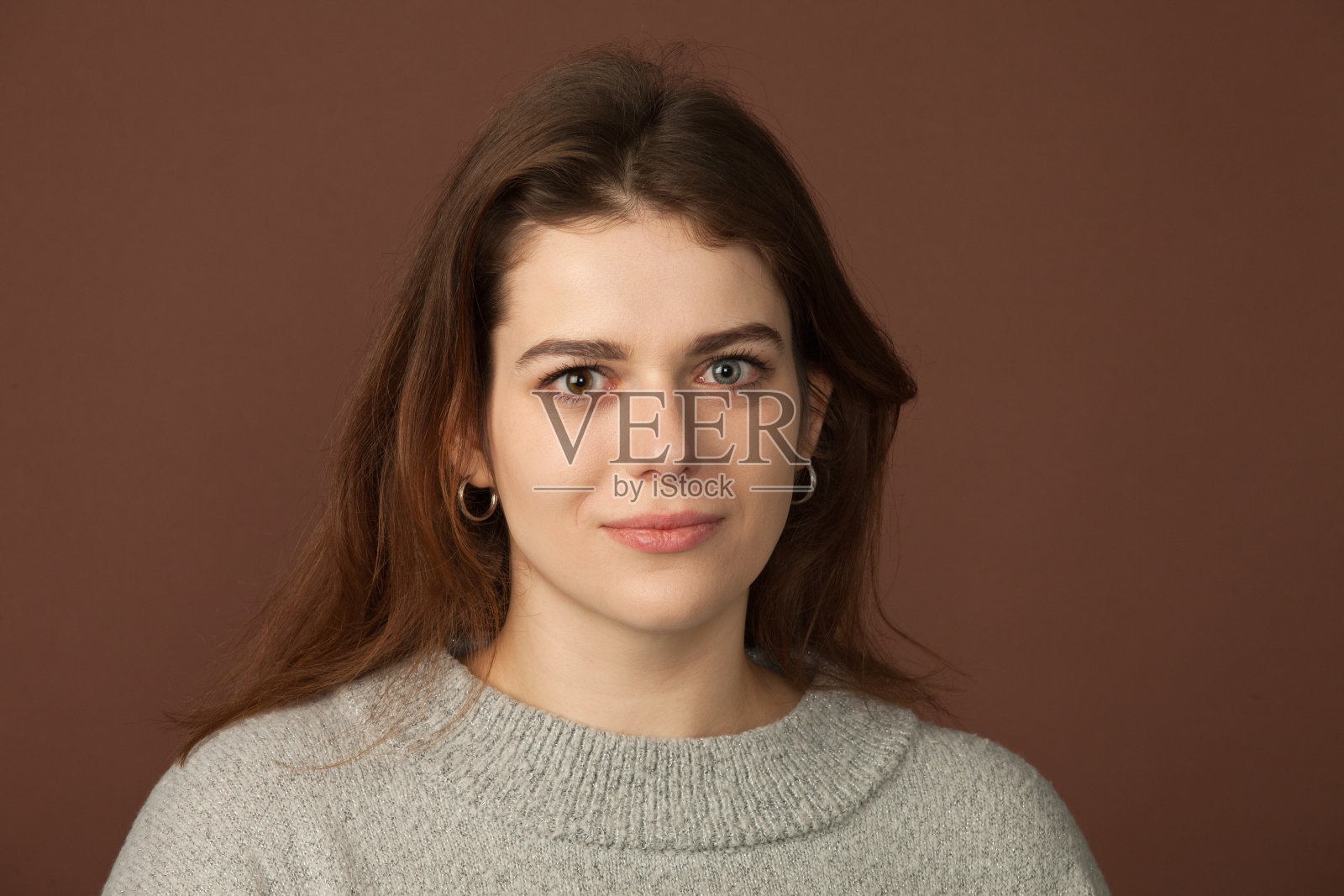 一名25岁女性在棕色背景上的工作室肖像照片摄影图片