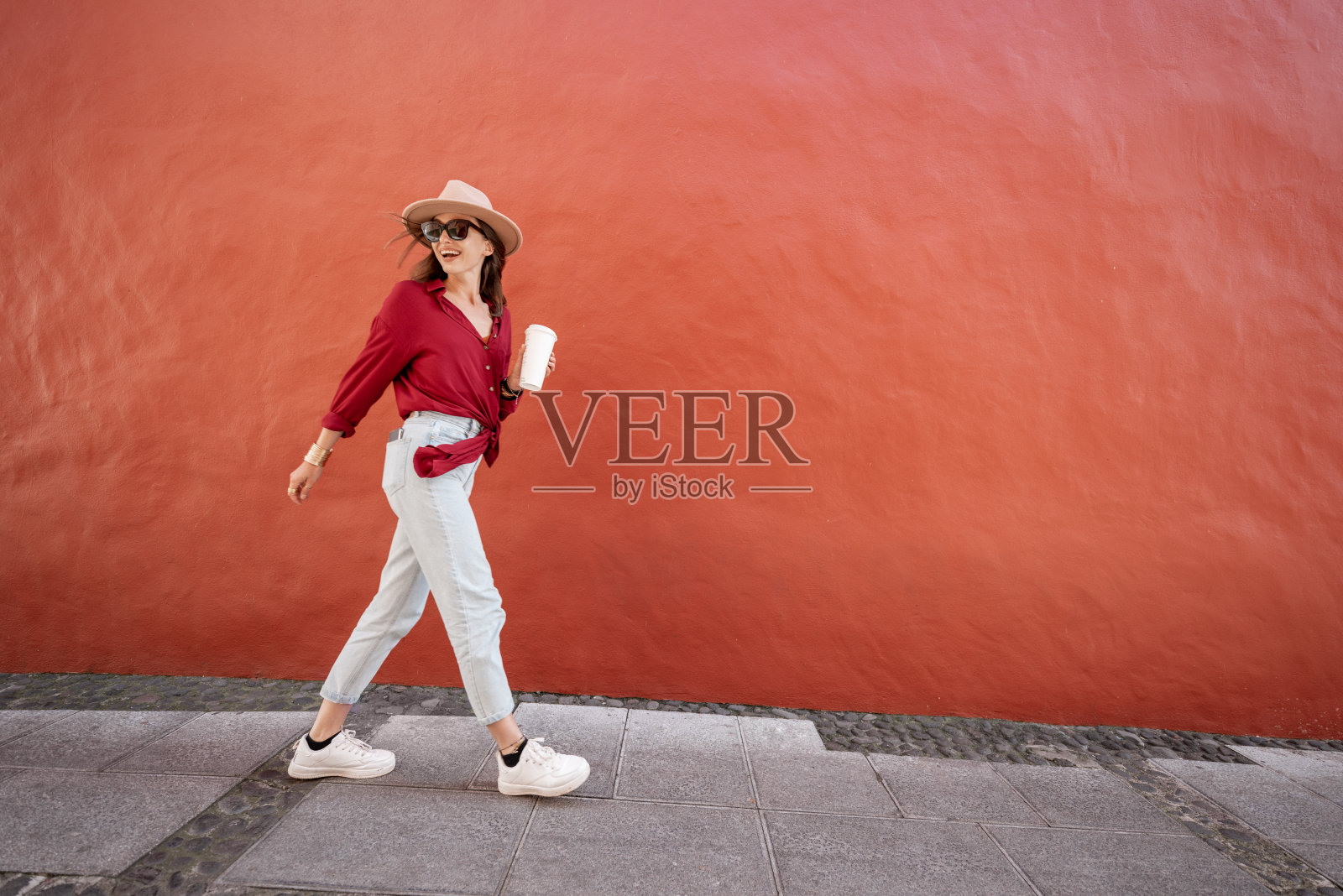 在红色墙壁背景下手拿咖啡杯的时尚女性肖像照片摄影图片