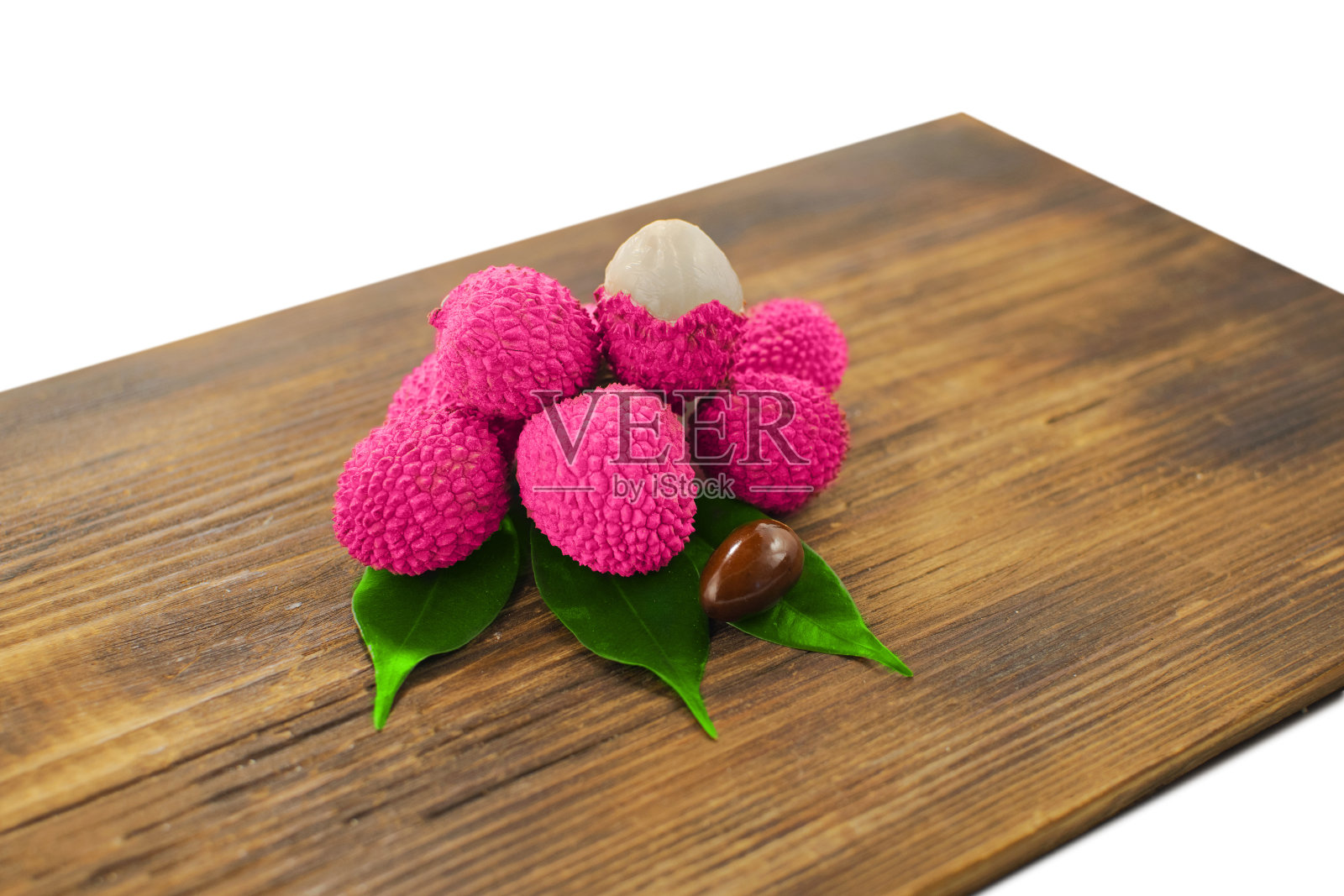 新鲜的荔枝和剥皮显示红色的皮和白色的果肉和绿色的叶子在木背景。荔枝带叶-热带水果。照片摄影图片