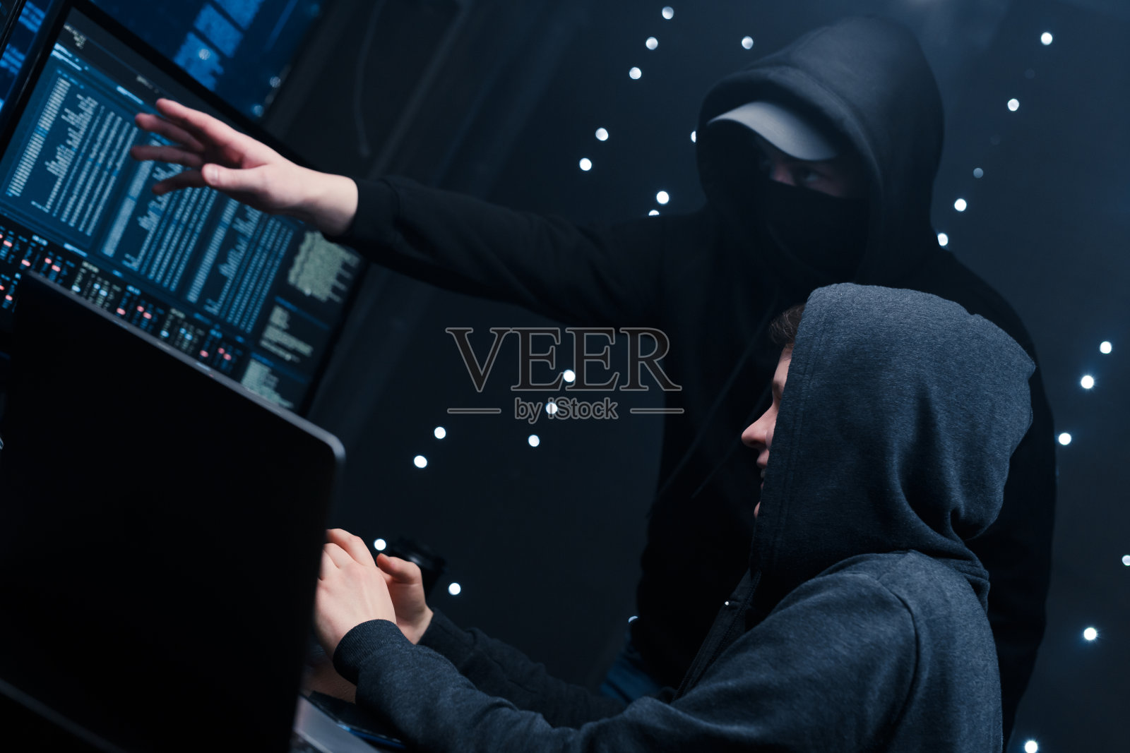 两名黑客看着监视器，讨论用来破坏安全系统的新软件代码。照片摄影图片