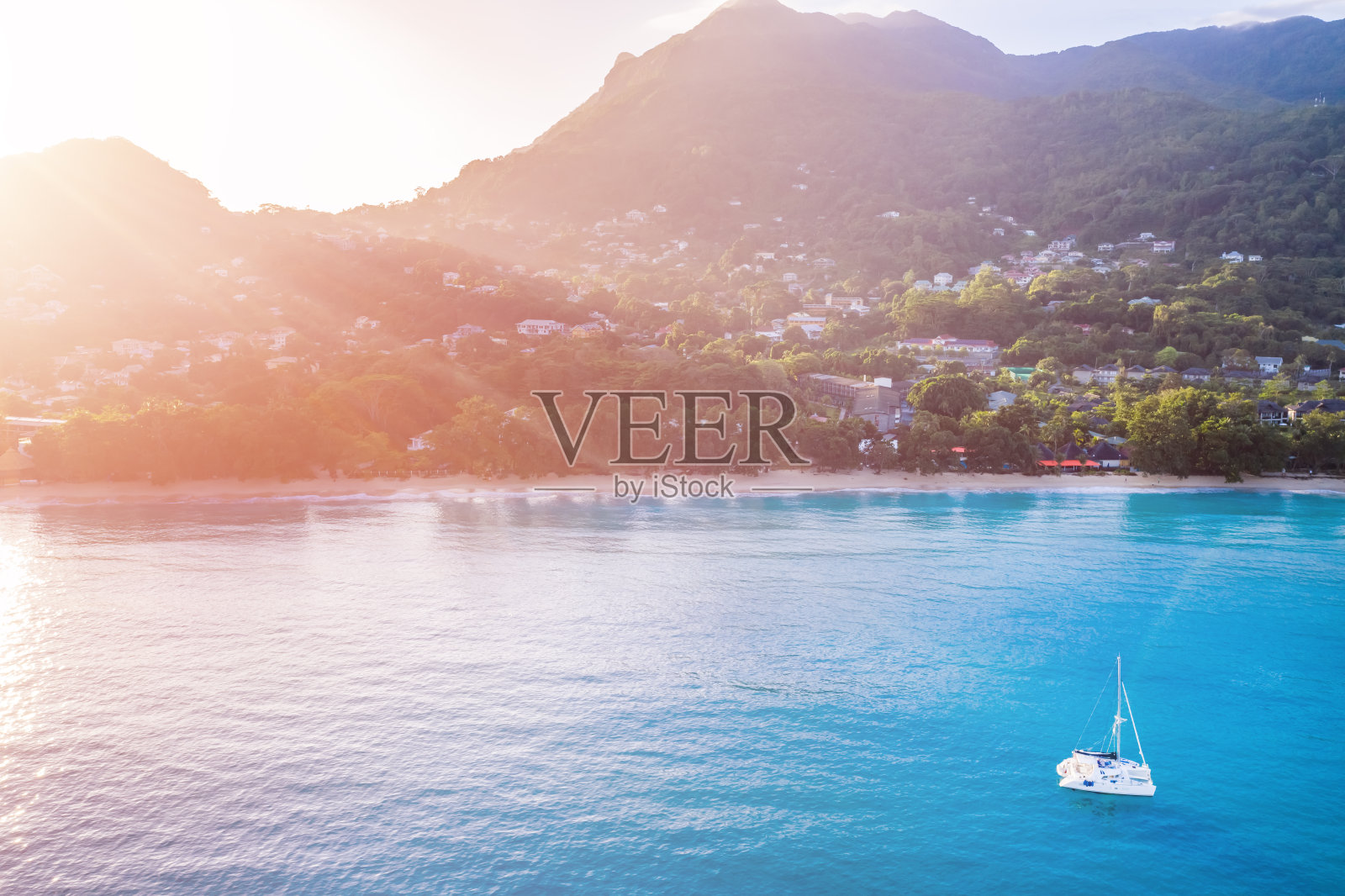 塞舌尔群岛的热带海岸线和蓝色海洋中的白色帆船。照片摄影图片