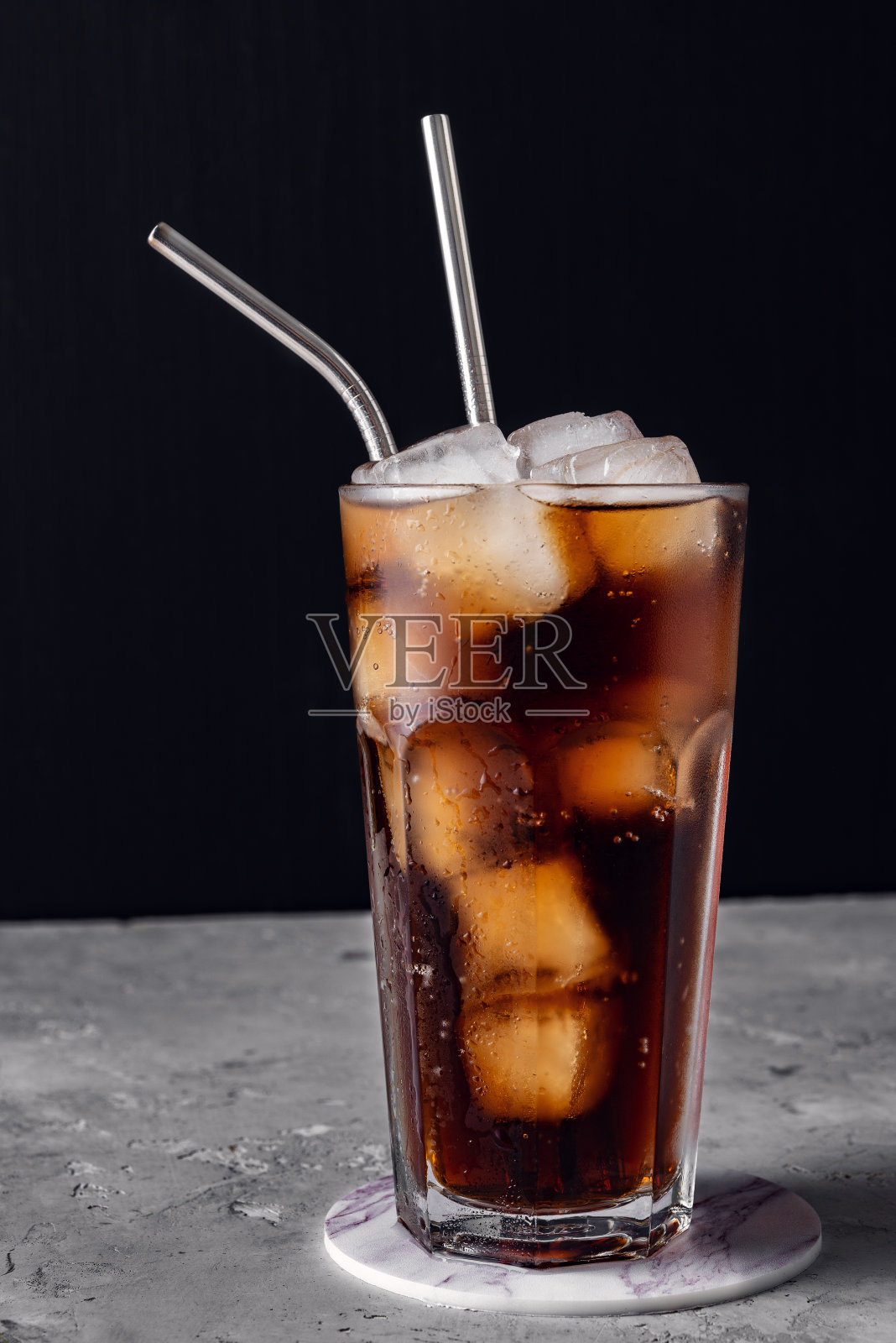 装有苏打水和冰块的玻璃酒杯，可重复使用的金属鸡尾酒吸管照片摄影图片