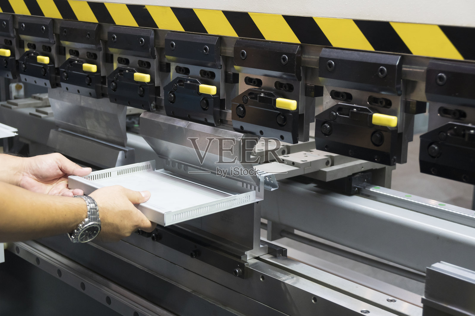 熟练操作员操作折弯机液压折弯机，用成型模具。照片摄影图片