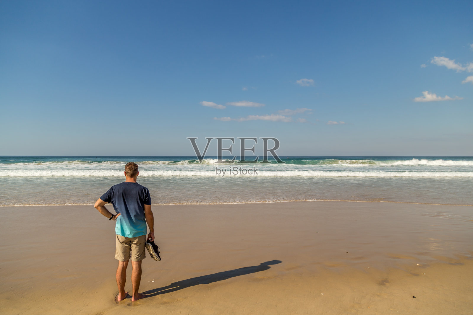 一个人站在海滩上望着海浪照片摄影图片