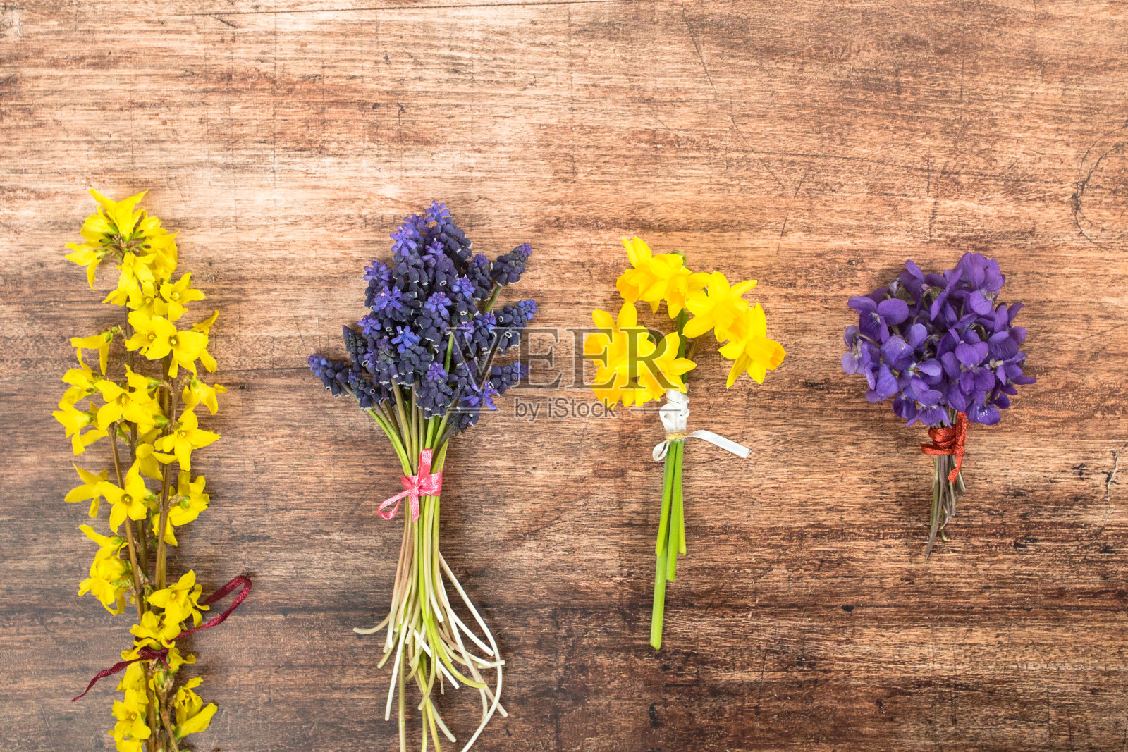 其中的第一朵春天的花在木质背景上，排列在花束中照片摄影图片