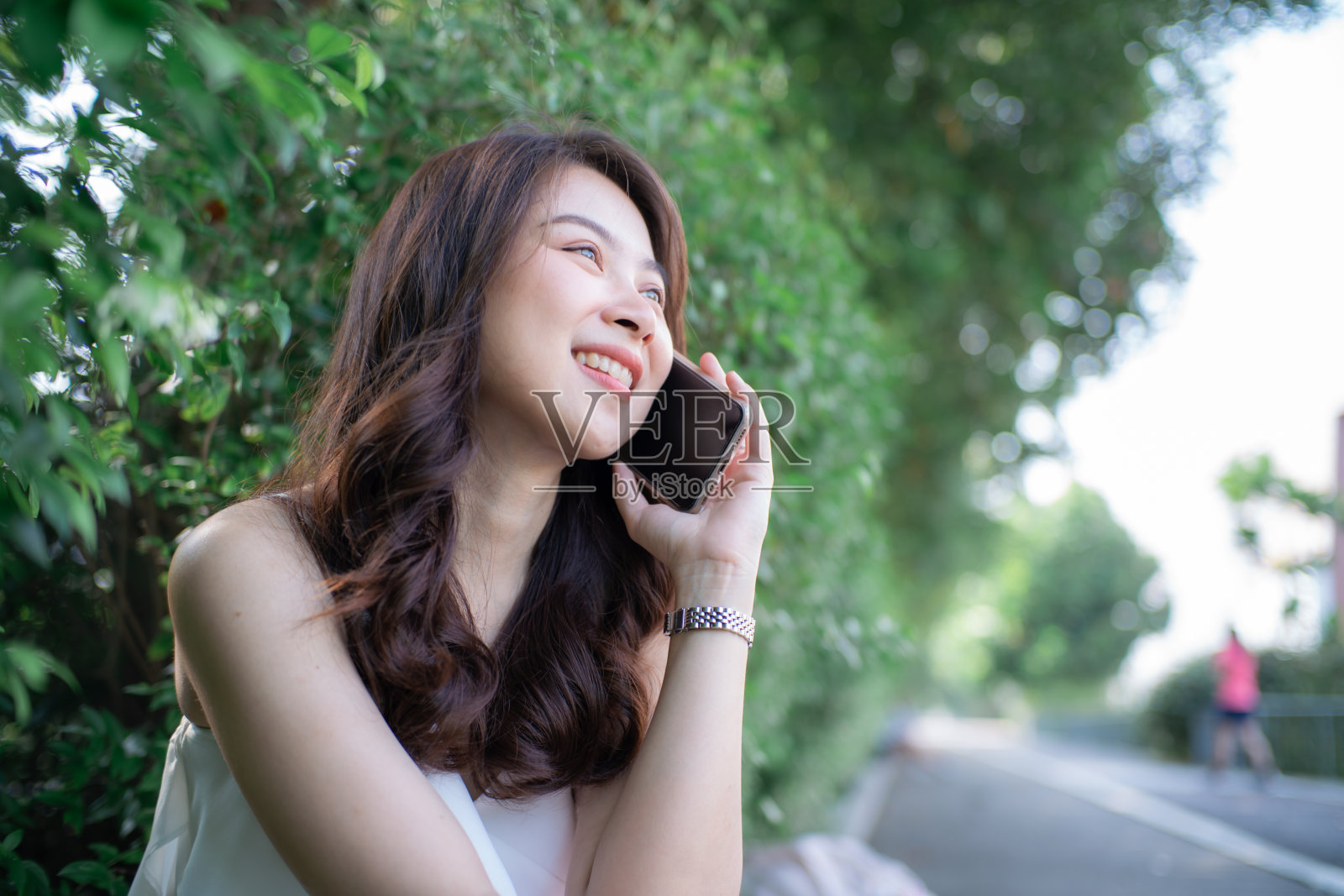 坐在绿草地上用智能手机交谈的亚洲美女照片摄影图片
