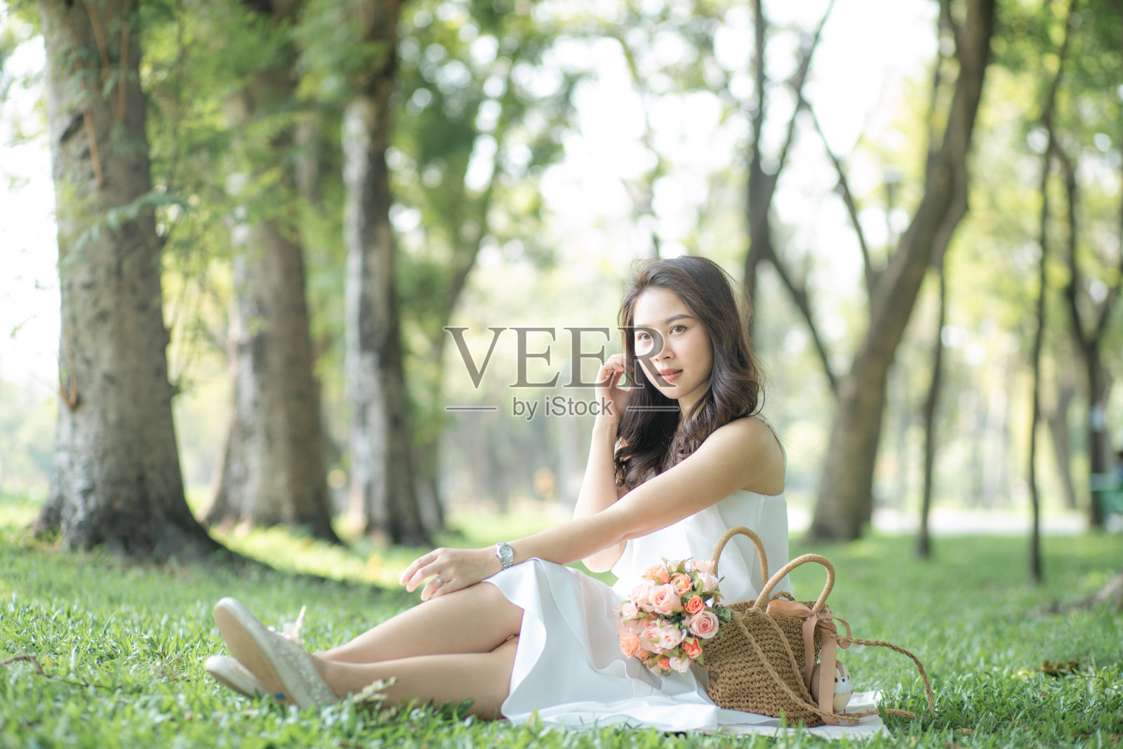 坐在绿草地上用智能手机交谈的亚洲美女照片摄影图片