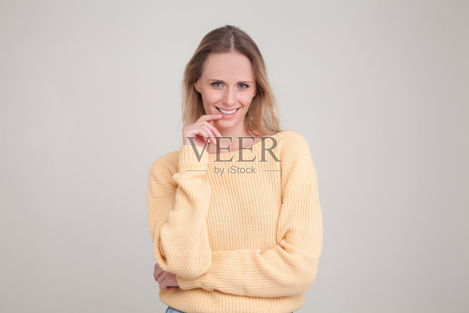 年轻金发女子微笑咬手指看向镜头的半身像照片摄影图片