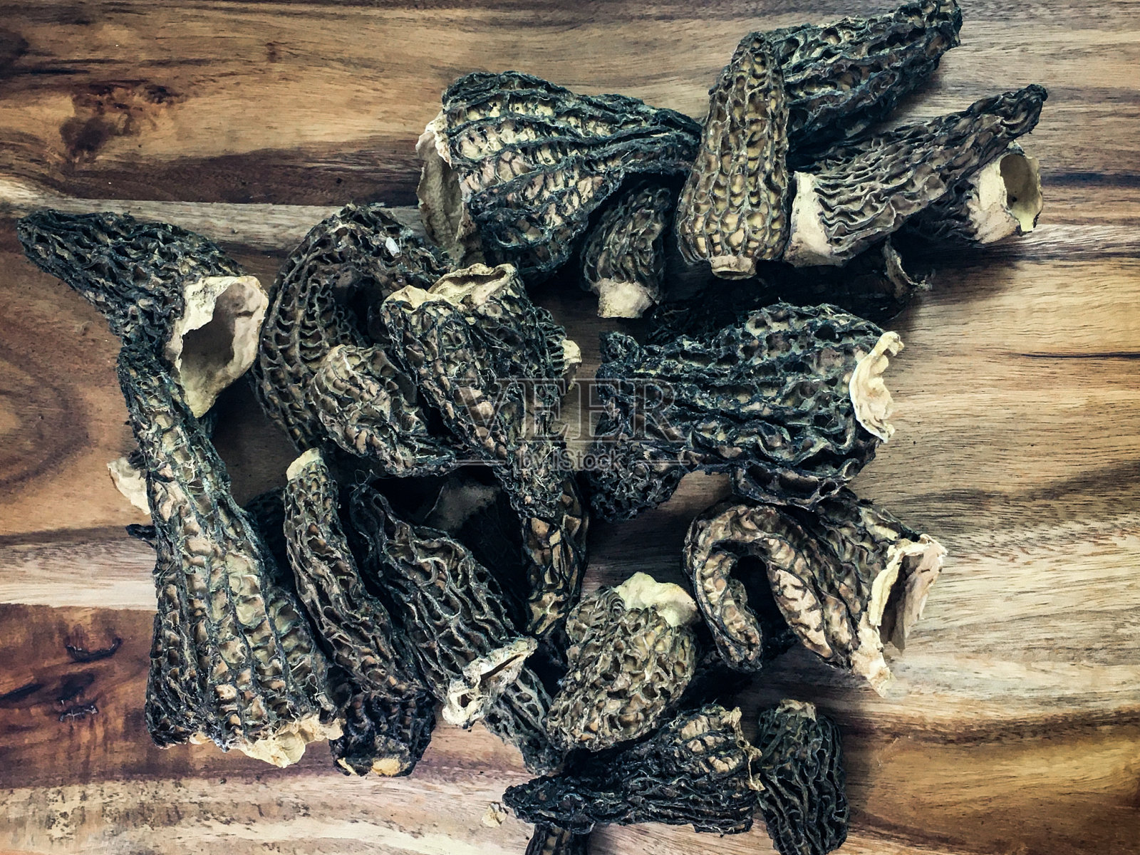 木纹背景上的干黑蘑菇。照片摄影图片