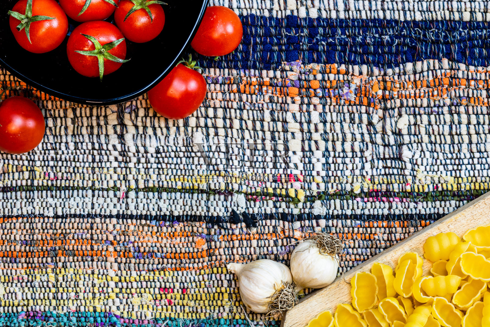 顶部细节视图的洋葱和新鲜成熟的樱桃西红柿在一个黑色的碗上的乡村餐巾。配料和食物概念照片摄影图片