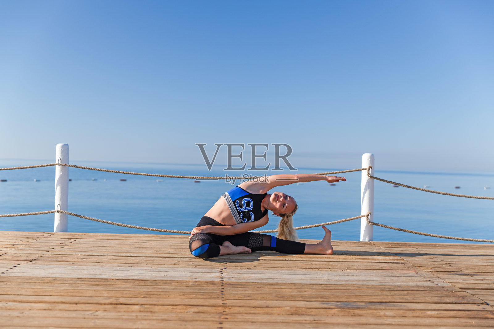 年轻女人在海边木制码头上做瑜伽照片摄影图片