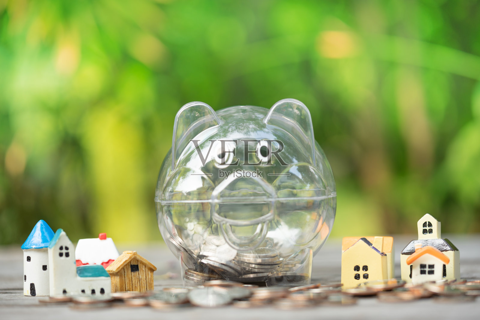 房屋模型与存钱罐，硬币堆积如山：住房储蓄、房产阶梯、抵押贷款和房地产投资概念照片摄影图片