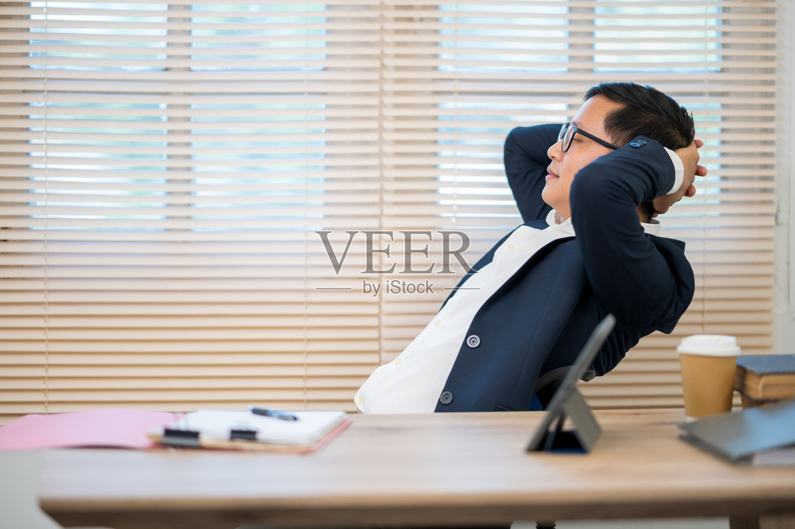 亚洲商人身穿黑色西装坐在办公桌前照片摄影图片