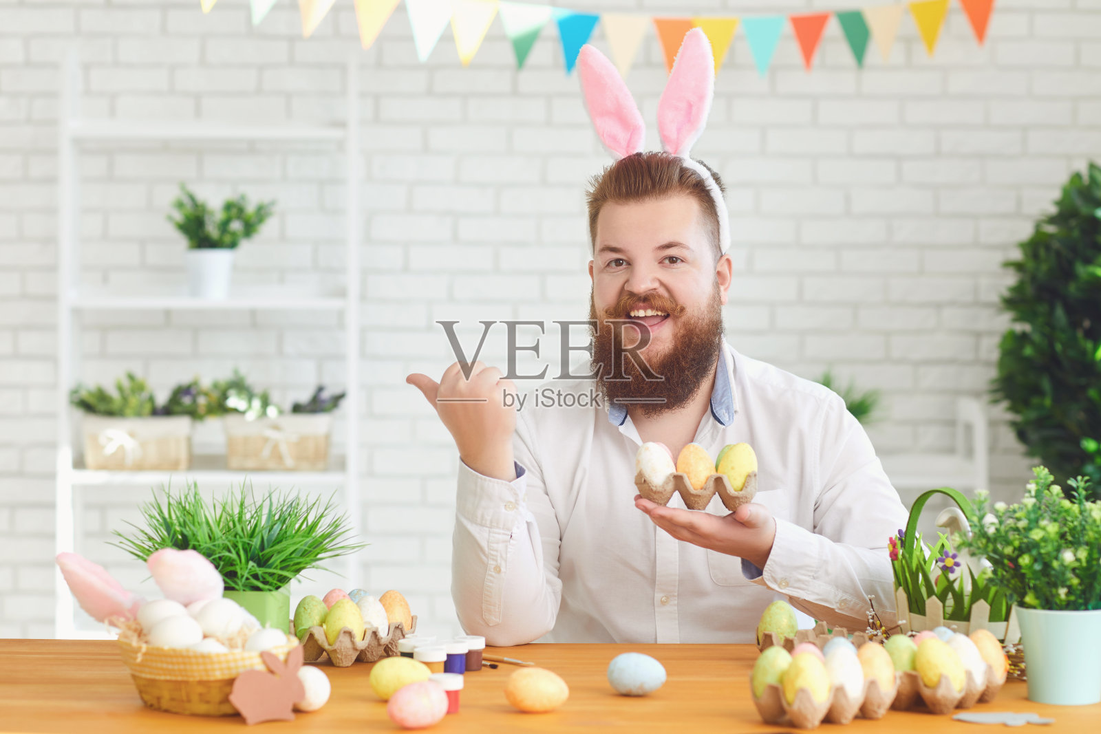 复活节快乐。一个有趣的胖男人在桌旁装饰彩蛋，背景是复活节装饰照片摄影图片