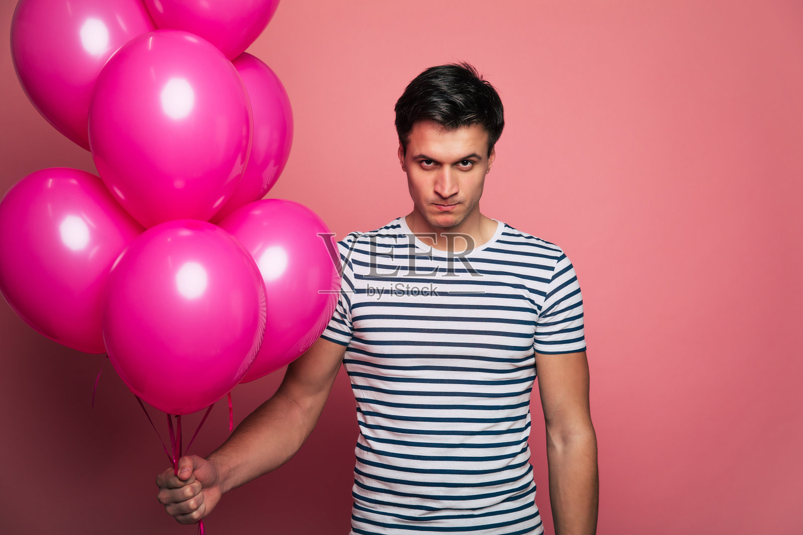 真实的,至爱的人类。英俊的年轻男子在休闲着装摆姿势与礼品和气球在手中生动的背景。照片摄影图片