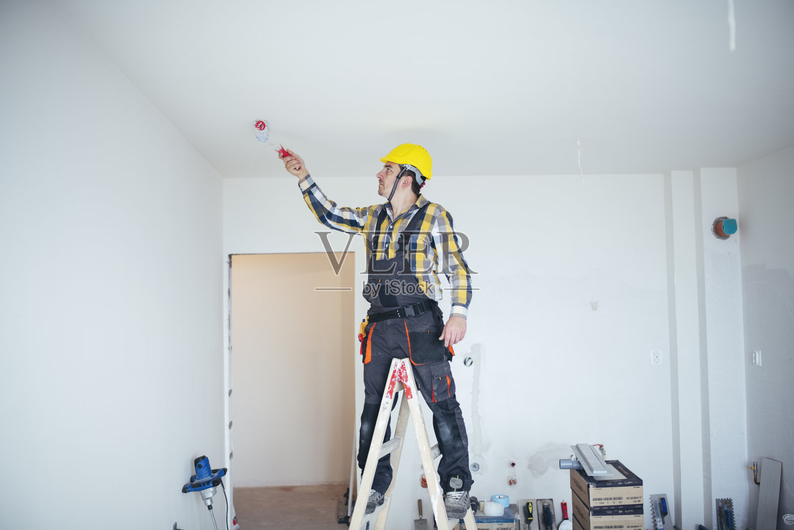 一个建筑工人用油漆滚轮粉刷天花板的全长图像照片摄影图片