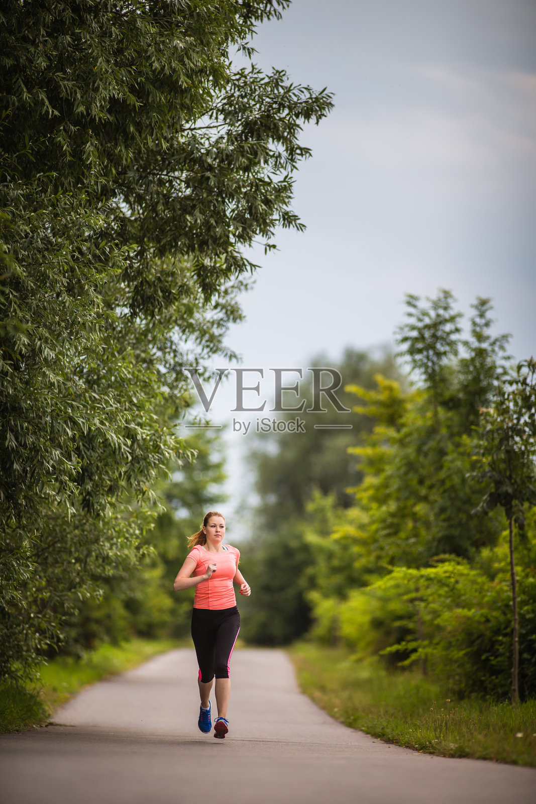 在一个阳光明媚的冬日/秋日，一个年轻女子在户外跑步照片摄影图片