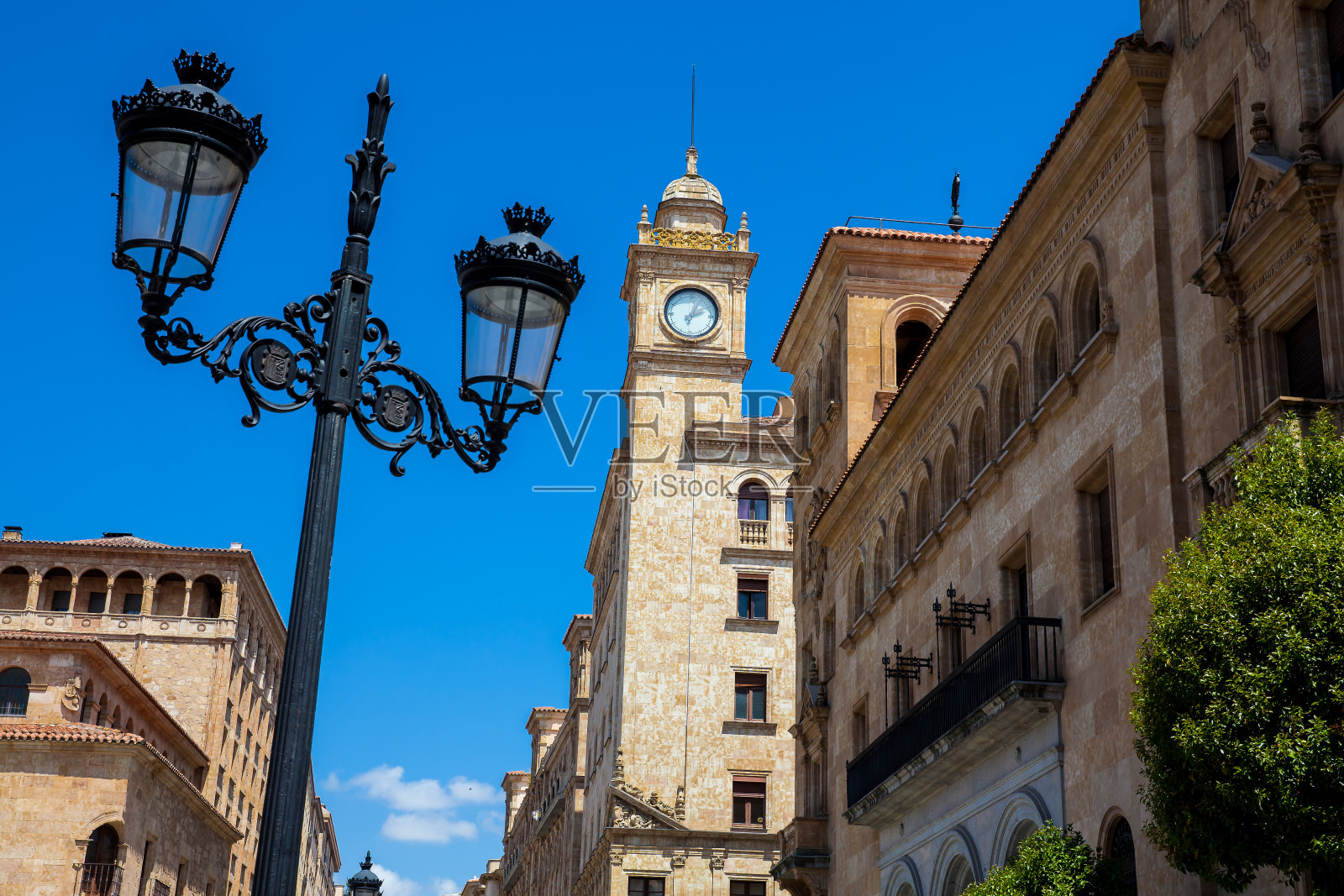 萨拉曼卡市中心萨莫拉大街上美丽的路灯和古董建筑的钟楼照片摄影图片