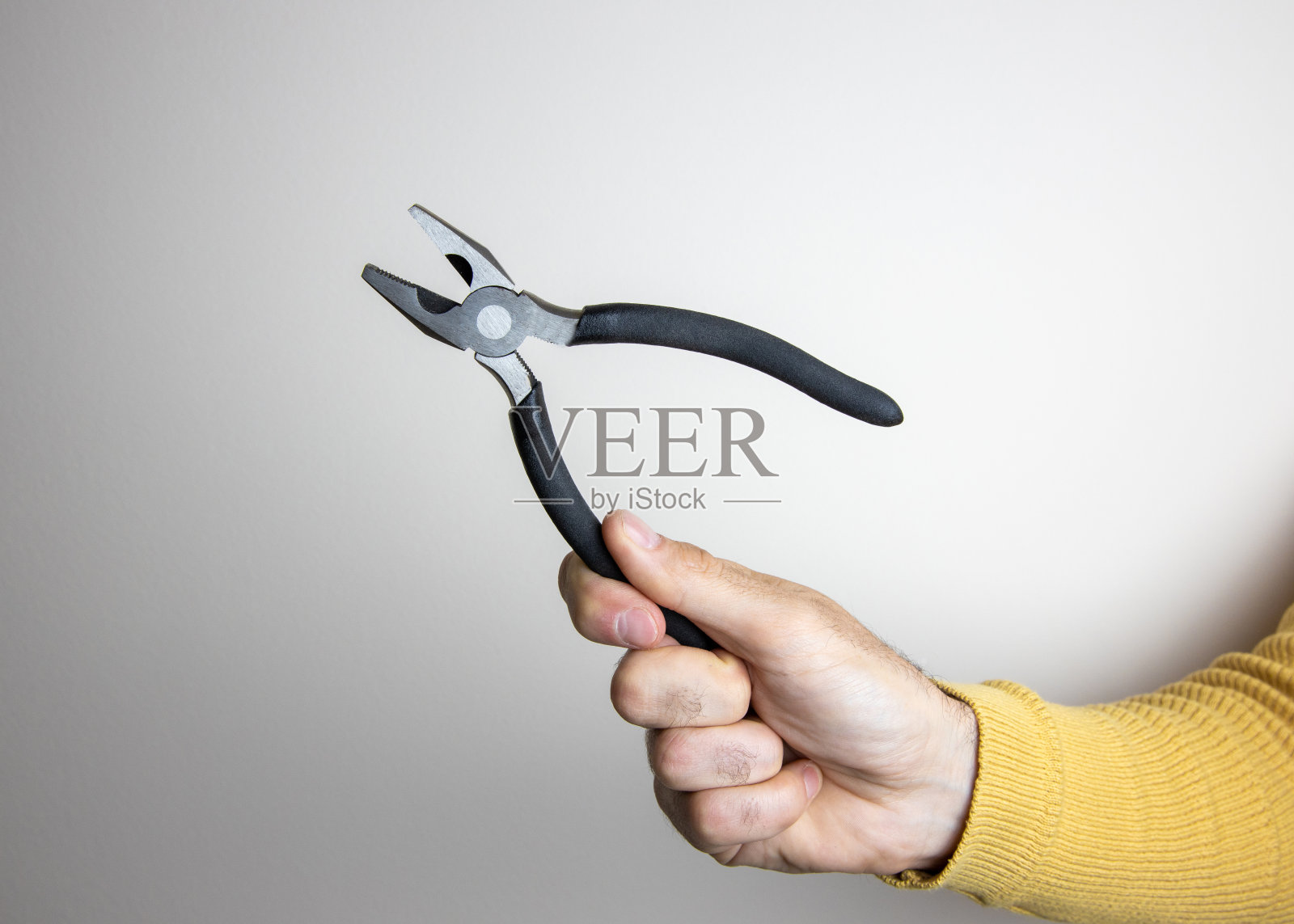 在空白背景上，男人穿着黄色毛衣，手持钳子的样机图片照片摄影图片