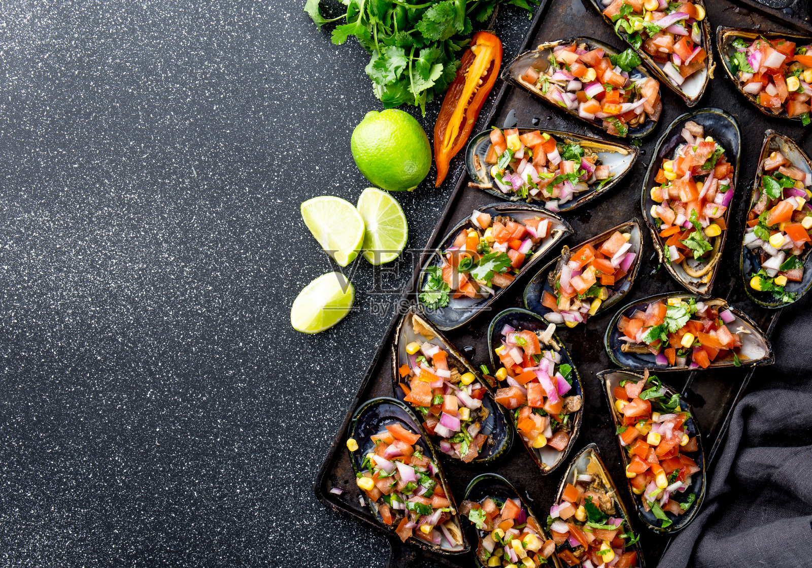 秘鲁的食物。chos ala chalaca。大贻贝，用紫洋葱，西红柿，玉米和柠檬调味。俯视图，黑色背景。传统秘鲁菜照片摄影图片