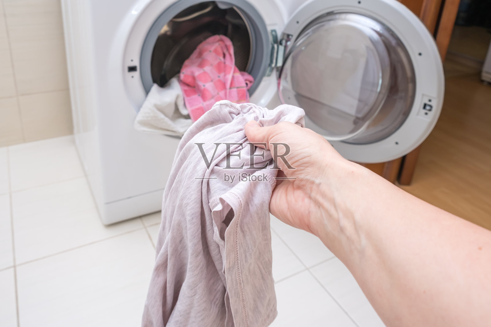 家庭主妇从洗衣机中取出或放入衣物照片摄影图片